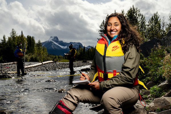 Women wearing a life jacket sits on the side of a river bank