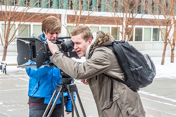 Two film students using film equipment outside