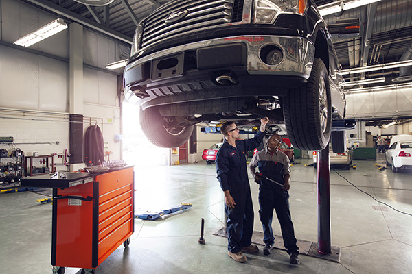 Two students work on the underside of a vehicle in the Clayton Carroll Automotive Centre.