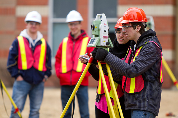 Two geomatics students setting up land surveying device
