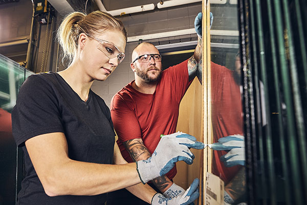 Two people working on glazing a mirror