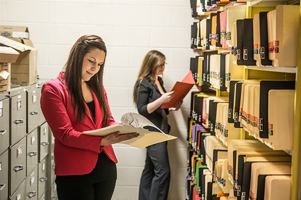 Two women reading files in a big document storage facility