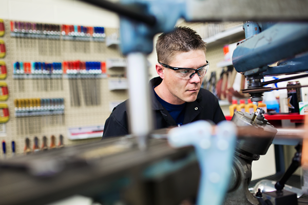 A Machinist apprentice wearing safety glasses works in a SAIT lab.
