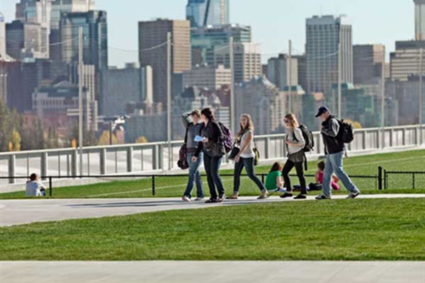 A group of students walks across the Cohos Commons field on SAIT campus.
