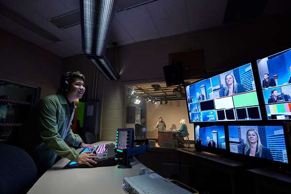 A Broadcast News student practices reporting the weather on a green screen in SAIT's television studio.