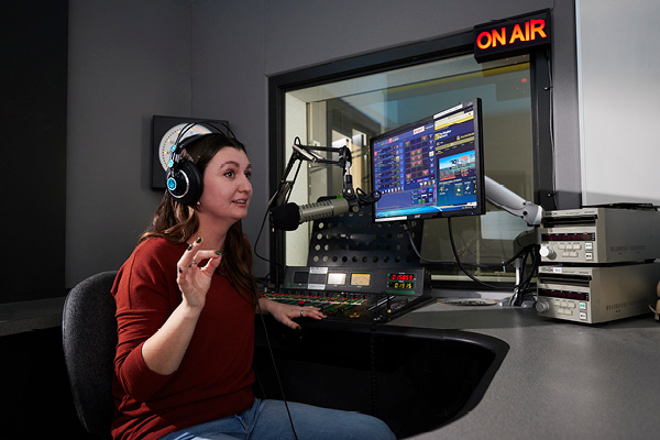Two radio students chat while broadcasting live inside SAIT's radio station.