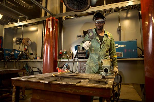 A steamfitter pipefitter apprentice works on a weld in a SAIT lab.