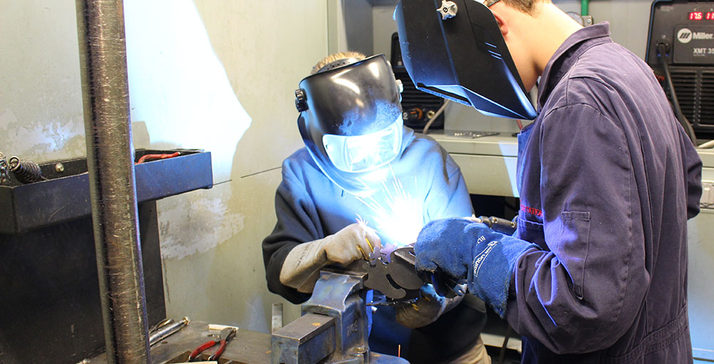 Two students work on a weld together
