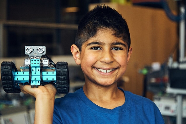 Young male student smiling and holding robot